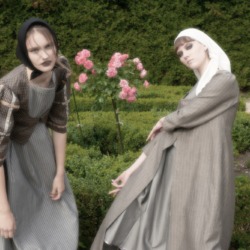 two women in a rose garden wearing ethnic costume inspired garmets